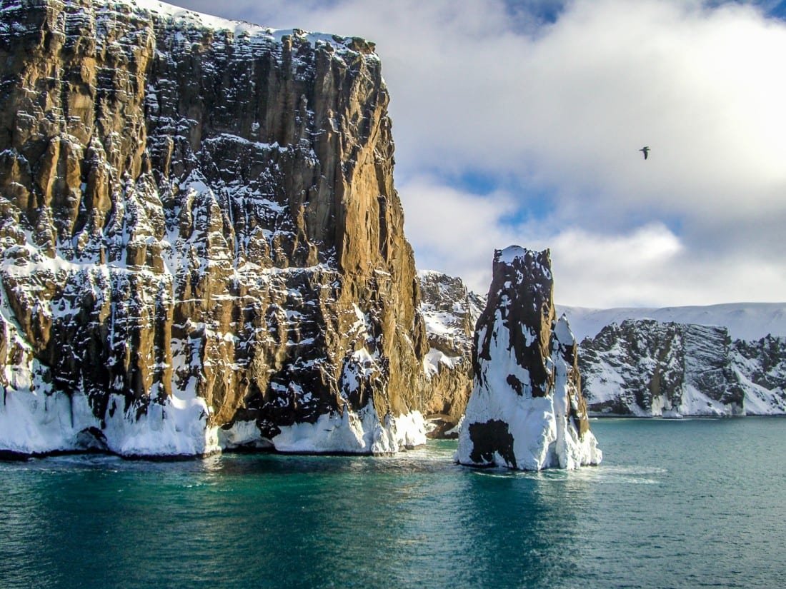 Antarctica-Private-Custom-Travel-Design-Cliff Sheer brown cliffs in the arctic ocean off the coast of Antarctica, photographed during an Antarctic cruise to Antarctica