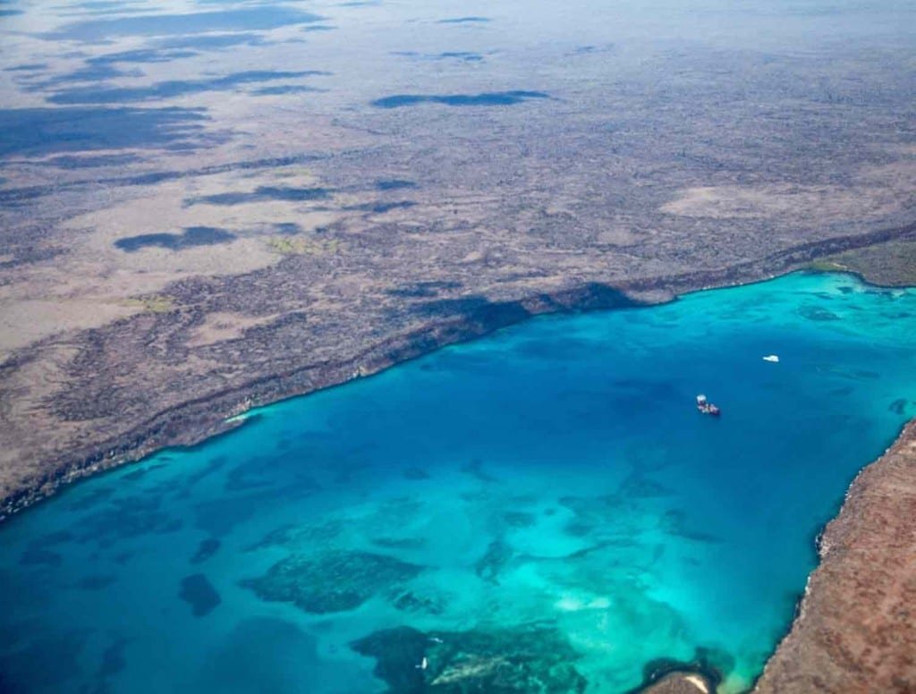 Custom-Travel-Galapagos-Vacation-Aerial-1 Aerial view of the Galapagos from a charter plane overlooking a group of Galapagos Yacht Charters in the clear blue waters below