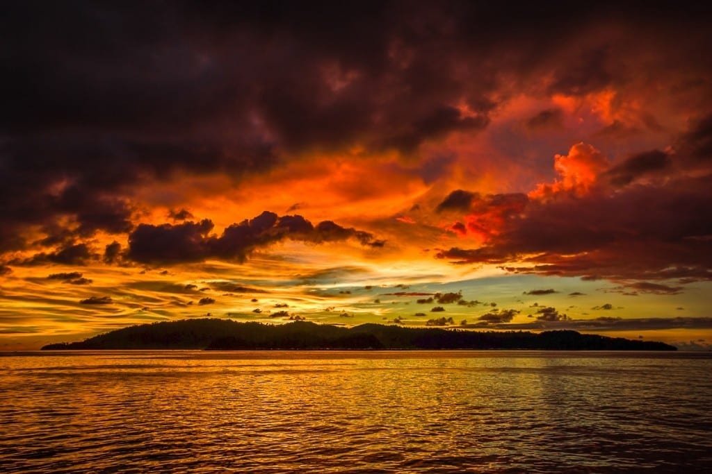 Belize-Private-Custom-Travel-Design-Sunset-2 A firey red and yellow sunset over the ocean, photographed on a family vacation to Belize