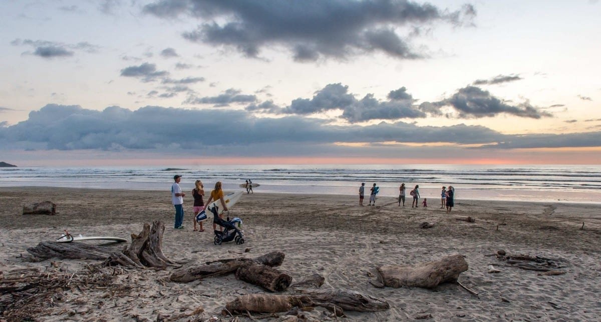 Costa-Rica-Custom-Private-Travel-Design-Playa-Guiones-2 Group of people on a surf vacation in Playa Guiones, admiring the sunset at Playa Guinoes in Central Nicoya, Costa Rica