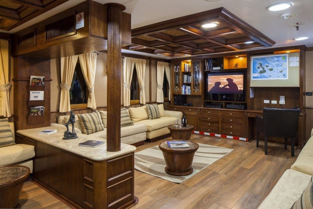 Grace-Inner-Saloon Large tan couch and tv in Inner Saloon of M/V Grace, a Galapagos Yacht Charter serving the Galapagos Islands