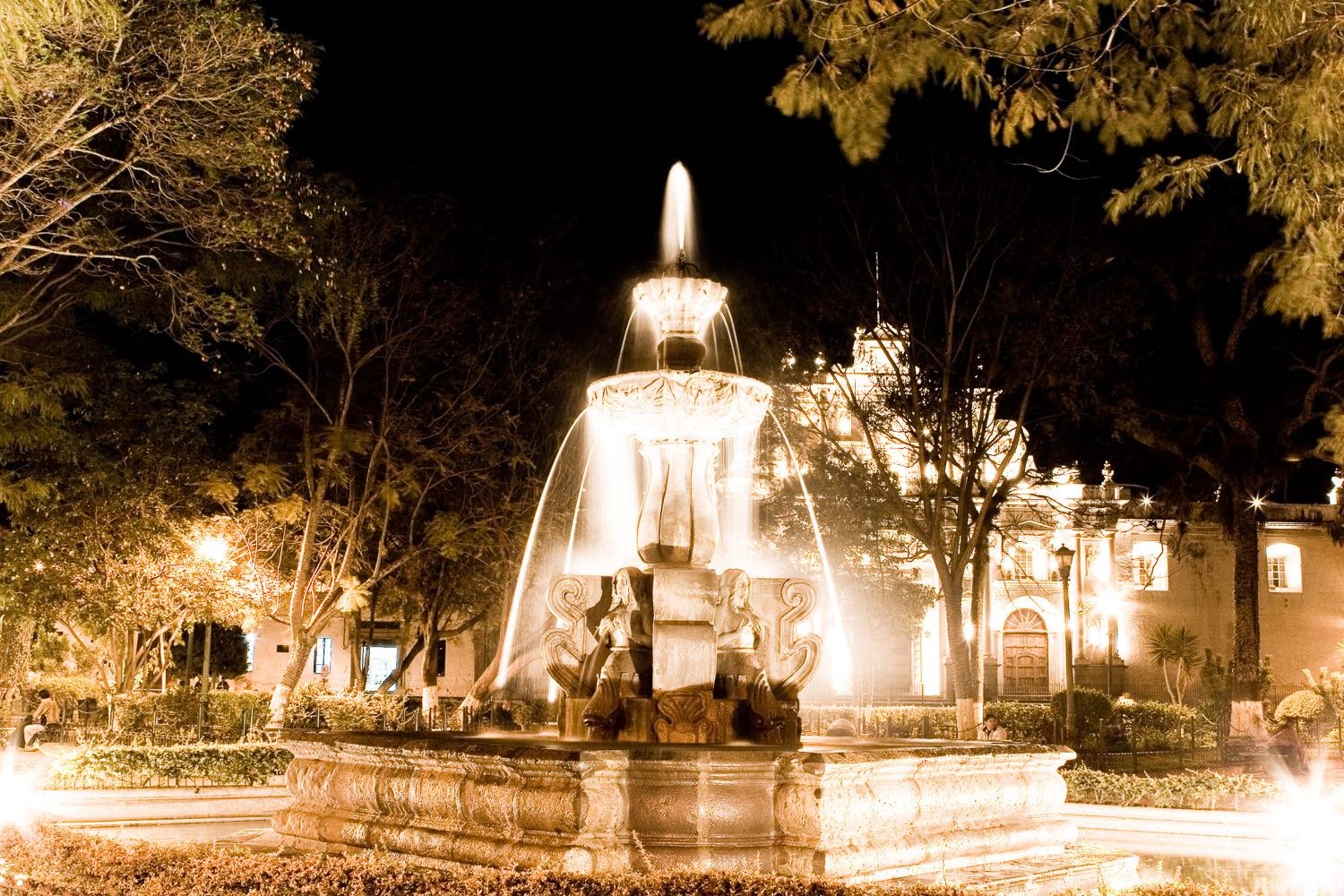 Guatemala-Custom-Travel-Design-Antigua-Fountain Illuminated, two-tiered fountain of the mermaids, at night in a plaza of Antigua, Guatemala