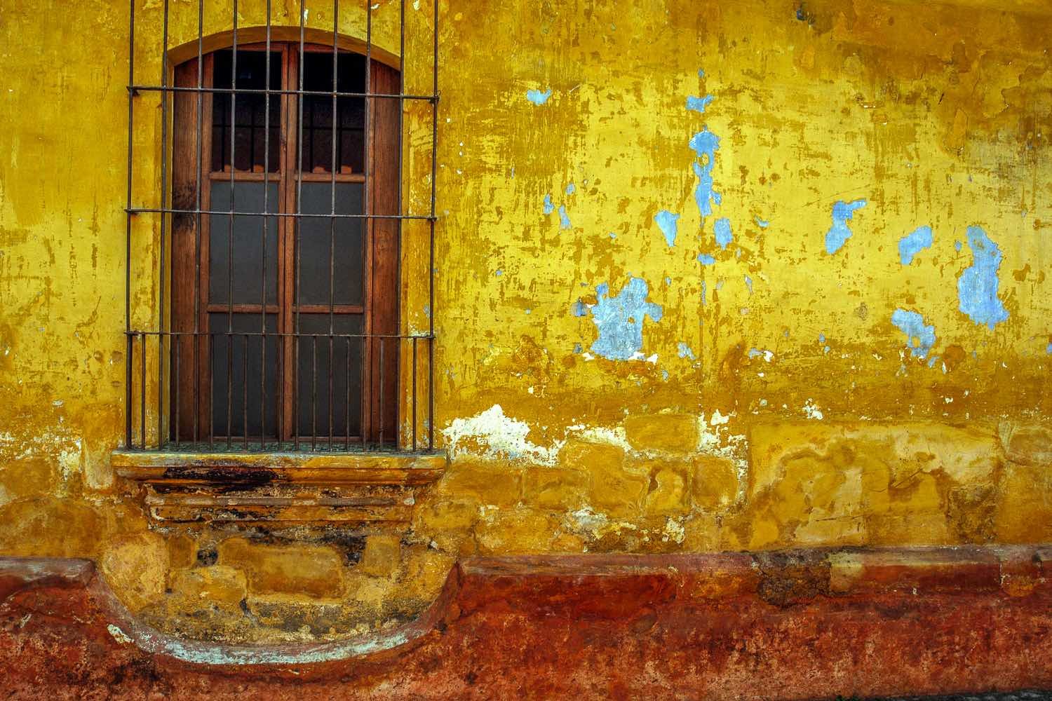 Barred-window-Antigua-Guatemala Old barred window set in a yellow and red wall.