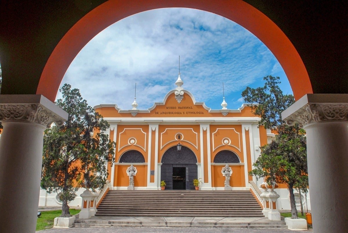Guatemala-Private-Custom-Travel-Design-National-Museum-Archaeology-Ethnology Guatemala's National Museum of Archaeology & Ethnology; Large orange building with white accents, photographed through red archway