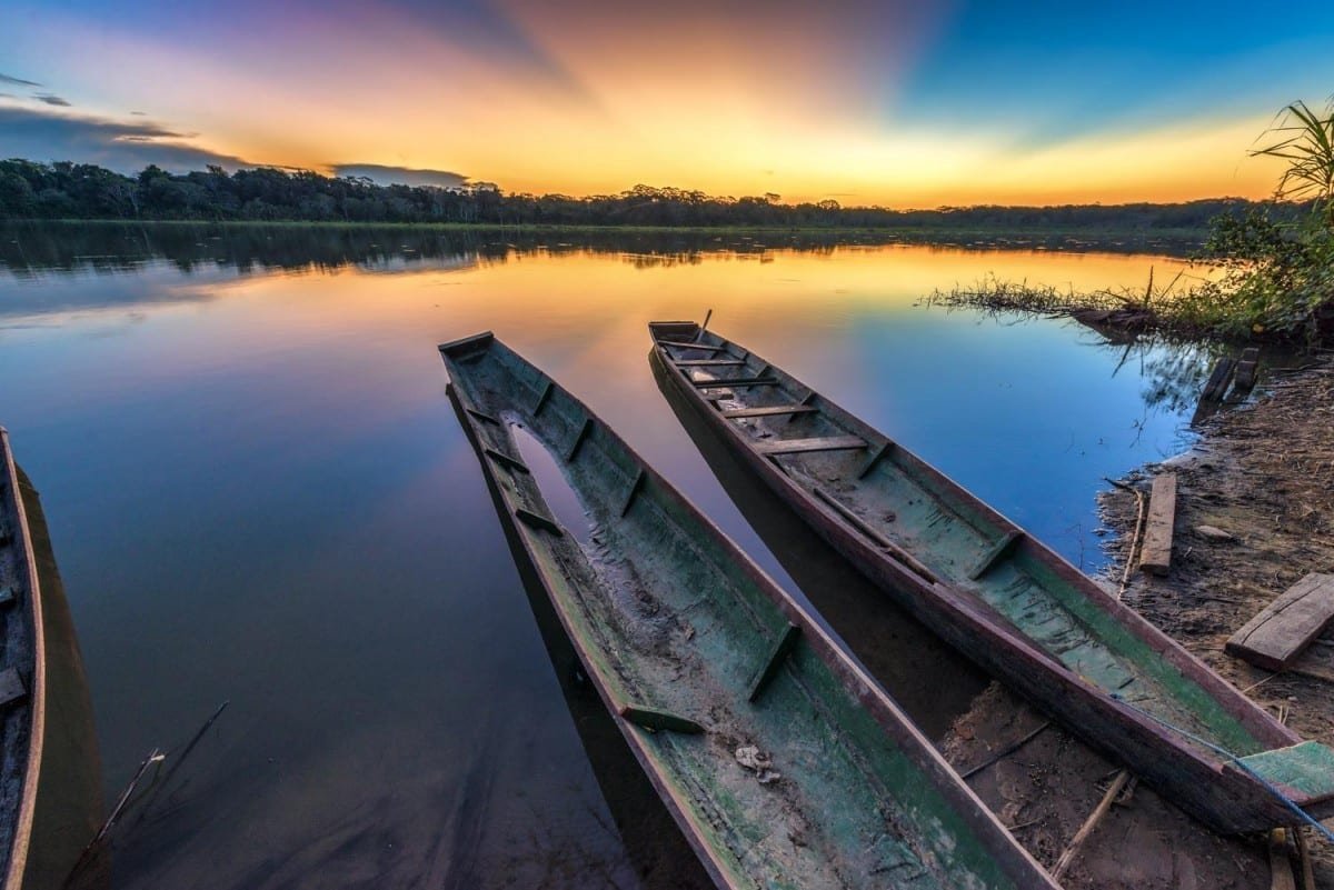 Landed-Travel-Private-Travel-Boats-Sunset-Madidi-Bolivia Two modest canoes sitting on a glass smooth lake in Madidi Bolivia