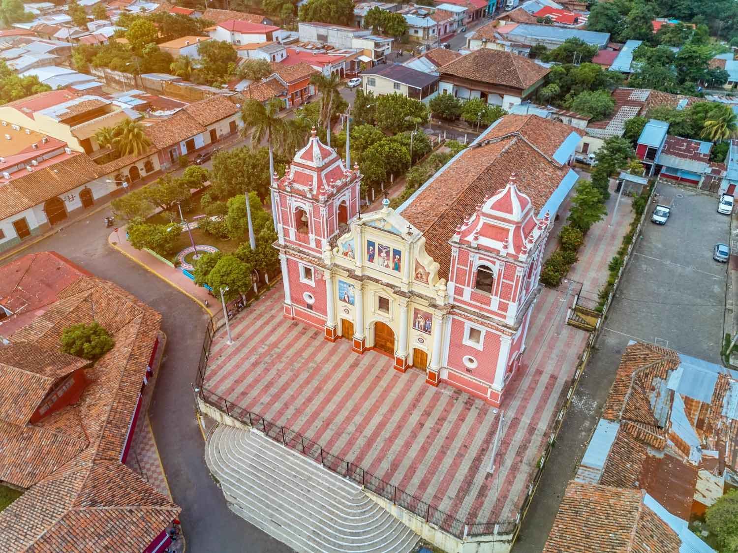 Leon-Nicaragua-Aerial-Church-Landed-Private-Travel of a large coral and yellow church with two tall pink and white bell towers, photographed from a helicopter charter in Nicaragua