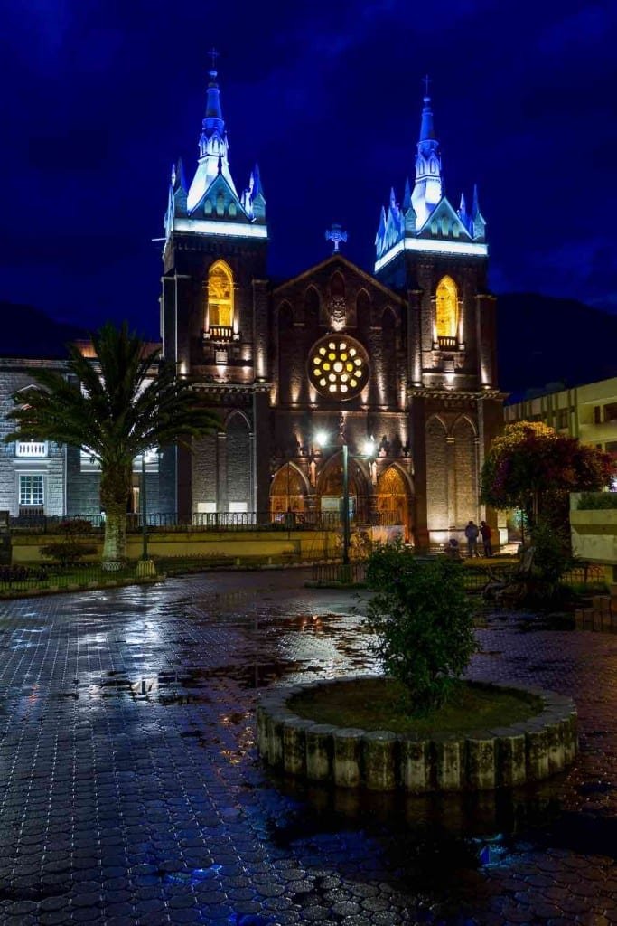 Private-Travel-Custom-Travel-Ecuador-Banos-Church-Night Twin bell towers of Our Lady of the Hold Water Church in Banos, Ecuador, illuminted at night in front of a large courtyard