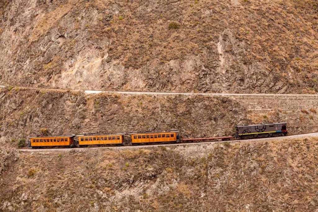 Private-Travel-Ecuador-Quito-Devils-Nose Black train engine leading a group of Orange Trail cars up the switchback track at Devil's Nose near Quinto, Ecuador