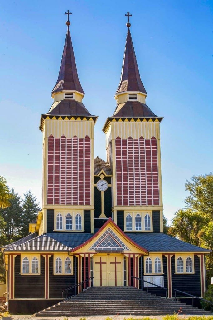 Private-Travel-Design-Chiloe-Chile-Panguipulli-Church Unique yellow and red Panguipulli church with two particularly tall pointed bell towers on Chiloe Island