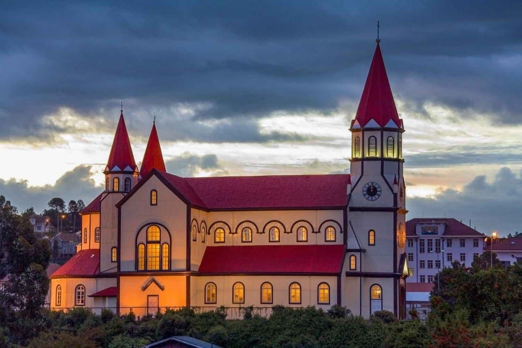 Private-Travel-Design-Lake-District-Chile-Puerto-Varas-Church Illuminated Iglesia Luterana. Large white church in Puerto Varas with red roof, one large tower and two smaller towers in Puerto Varas Chilean Lake district