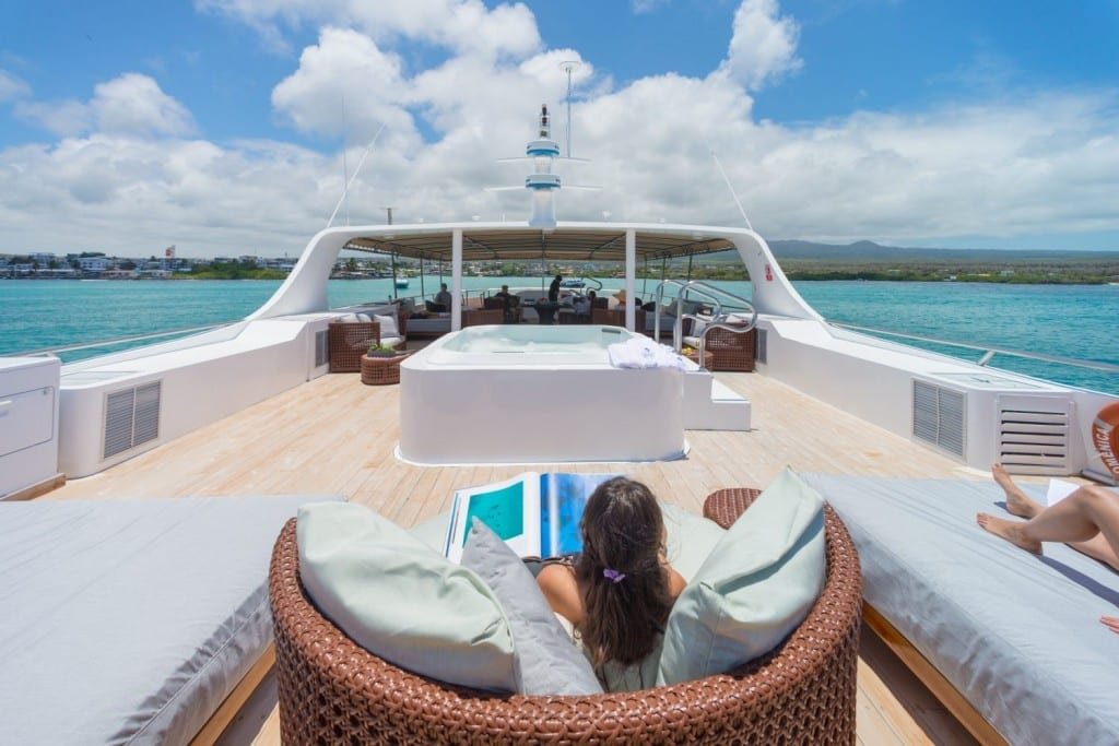 Sea-Star-Gapagos-Yacht-Sundeck-Hot-tub-Woman Woman sitting on the sundeck of Galapagos yacht Charter Sea star journey, facing a large white hot tub on the main deck