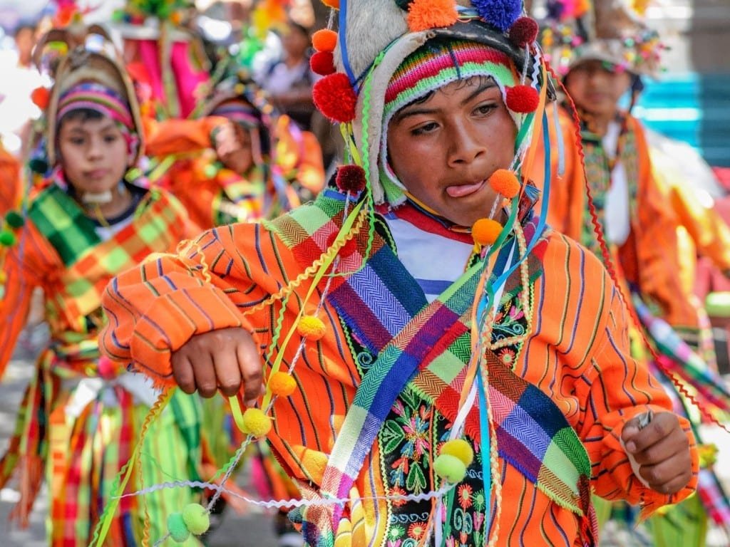 Landed-Travel-Private-Travel-Fiesta-Sucre-Bolivia Bolivian boy wearing traditional Bolivian clothing with many vibrant colors, celebrating a local Fiesta in Sucre, Bolivia