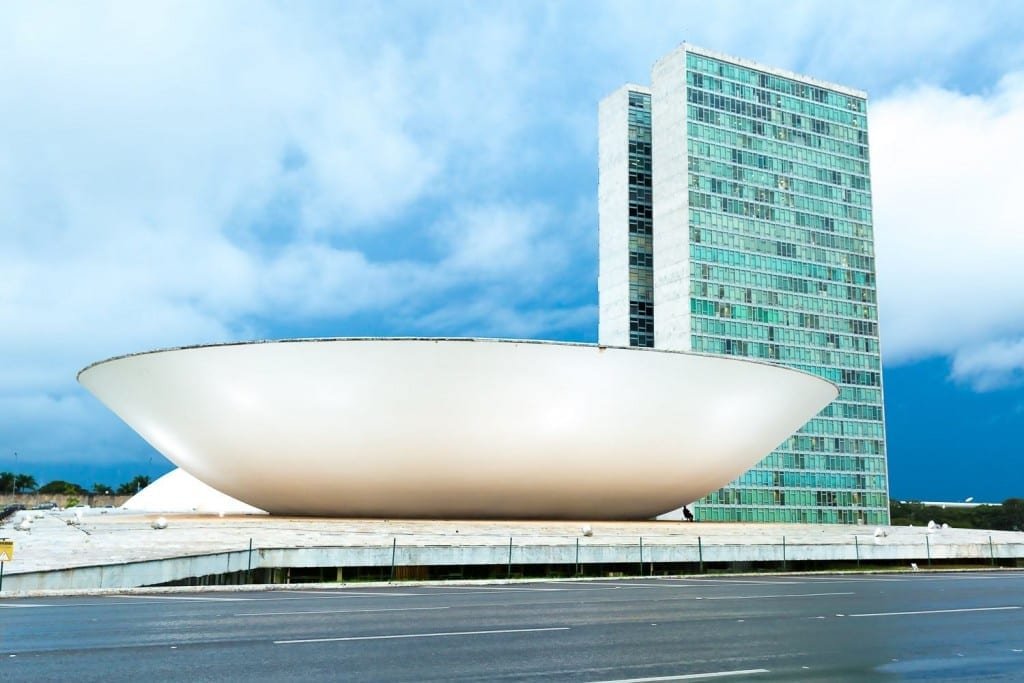 Private-Custom-Travel-Design-Brazil-Congress-2 Giant white bowl-like sculpture outside a teal and blue building in downtown Brasilia, Brazil, photographed during executive travel in the region