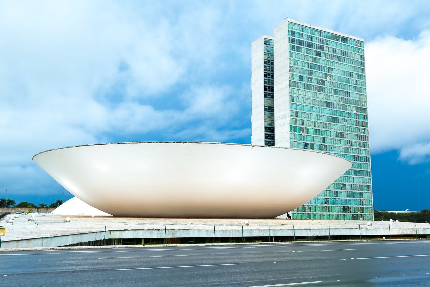 Private-Custom-Travel-Design-Brazil-Congress-2 Giant white bowl-like sculpture outside a teal and blue building in downtown Brasilia, Brazil, photographed during executive travel in the region