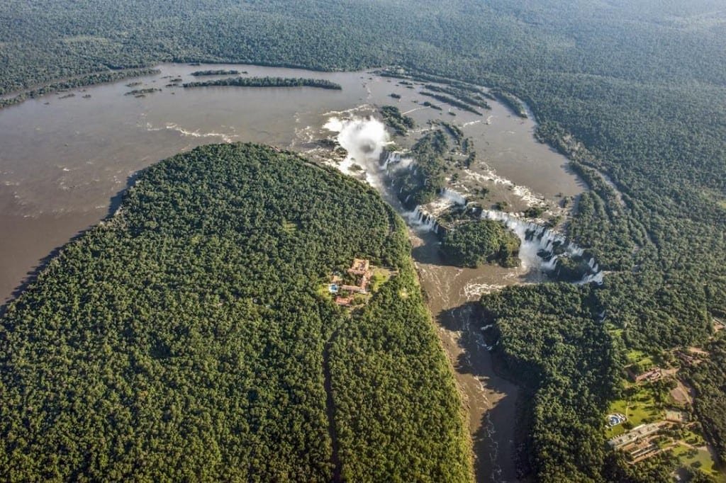 Private-Custom-Travel-Design-Brazil-Iguacu-Aerial-Wide Aerial photo taken from helicopter charter tour over Iguacu falls in Brazil showing the massive brown Iguacu river surrounded by dense forest