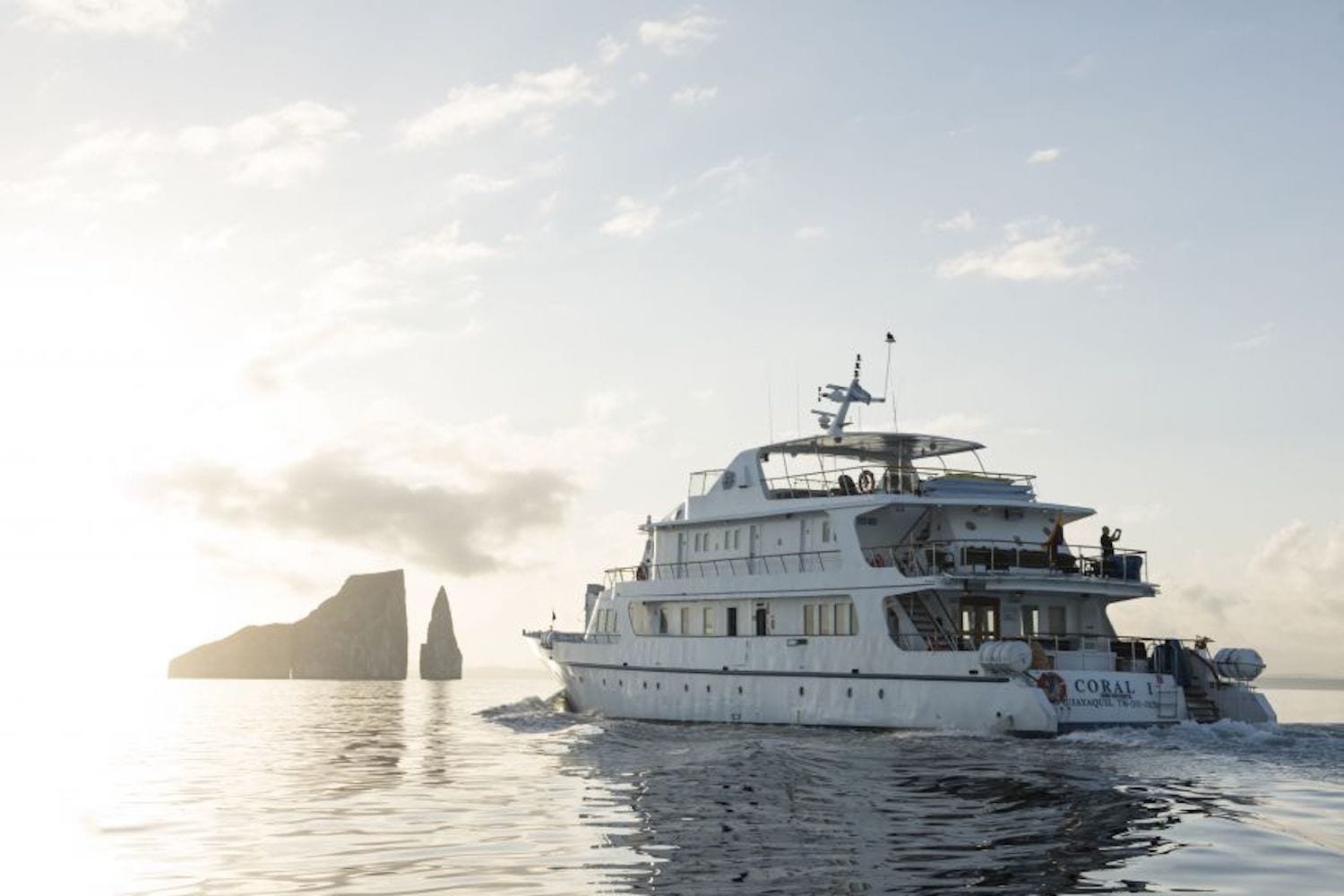 coralisunset Coral II, large white Galapagos Yacht Charter cruising towards kicker rock at sunset