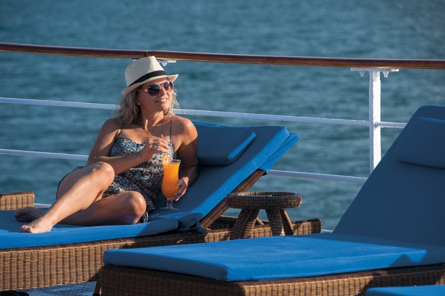 loungingonthepool Woman lounging in blue chair by pool onboard Galapagos Cruise ship M/V Legend