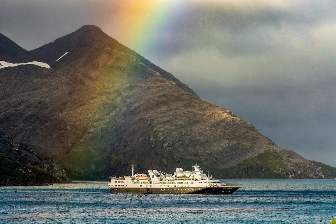 Antarctica-Luxury-Cruise-Travel-Silversea Large blue and white Antarctica Luxury Cruise ship under a rainbow in the Silversea