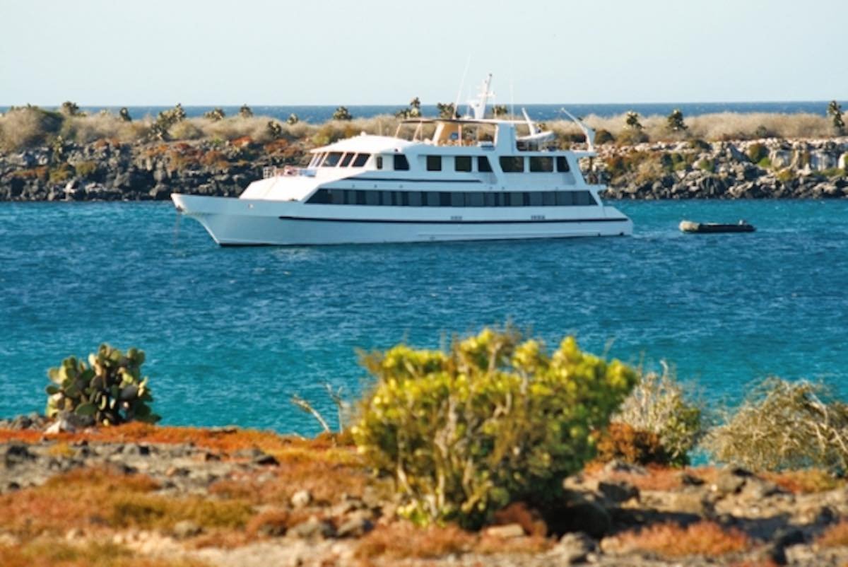 Integrity-Yacht-Charter-Galapagos-3 Large white M/Y integrity, One of the Galapagos luxury charters LANDED books in the Galapagos archipelago, cruising in aqua blue waters close to the shoreline