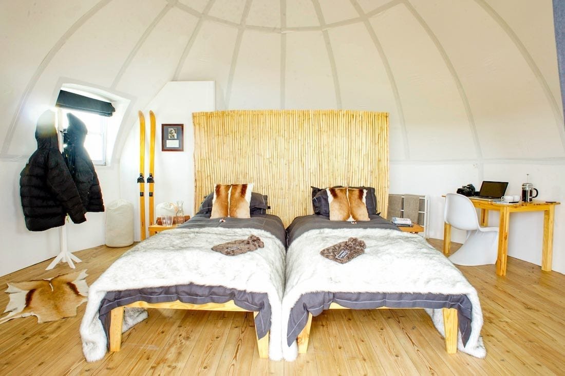 Luxury-Antarctica-Hotel-pod-Interior Bamboo floors and bright interior of luxury camping pod at Antarctic hotel Whichaway camp. Twin beds with luxury linens and modern bamboo appointments throughout. Skis leaning in the corner.