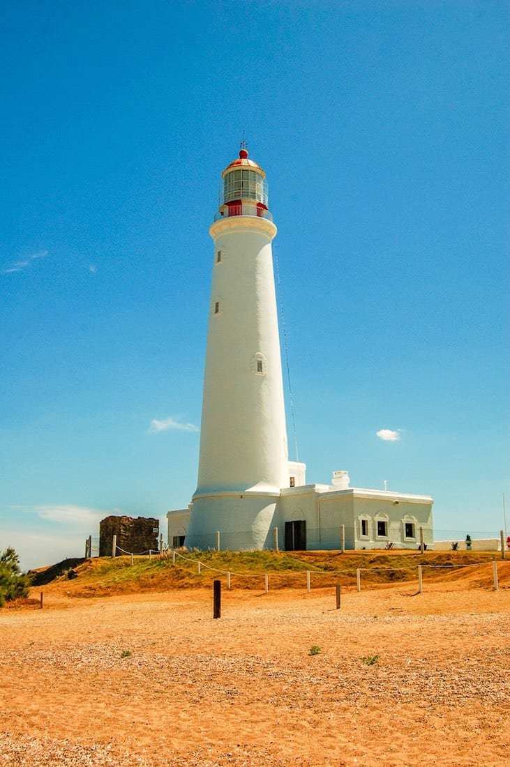 White lighthouse Large white lighthouse surrounded by brown shores of La Paloma, Uruguay
