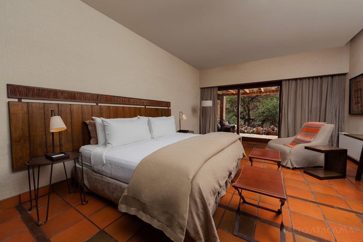 AA_Hab_Tilo Altoa Atacama's Tilo room has a white king size bed, lounge chair and outdoor views.