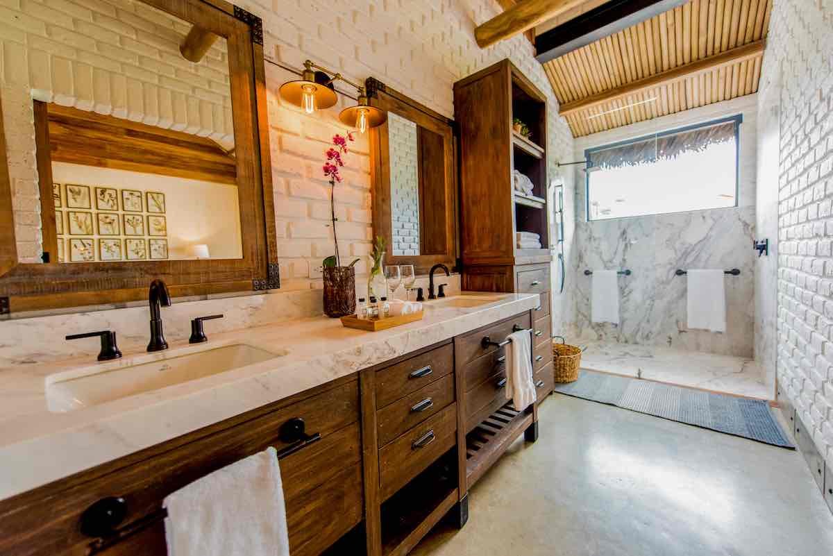 Bathroom-Hacienda-La-Danesa The bathroom at Hacienda La Danesa has white brick, wood drawers and two vanity mirrors.