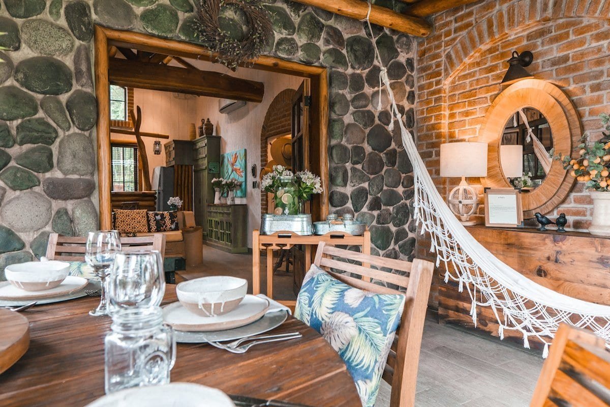 Family Garden Cottage The garden cottage features stone walls, a white hammock and wooden tables.