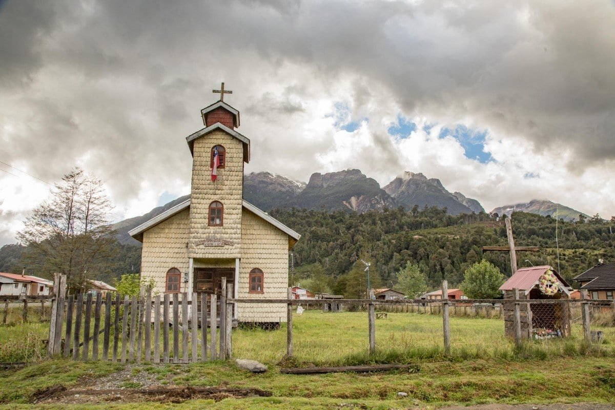 Landed-Travel-Chile-Aysen-211 Small historic white brick church with single steeple under a cloudy sky in Chilean Patagonia