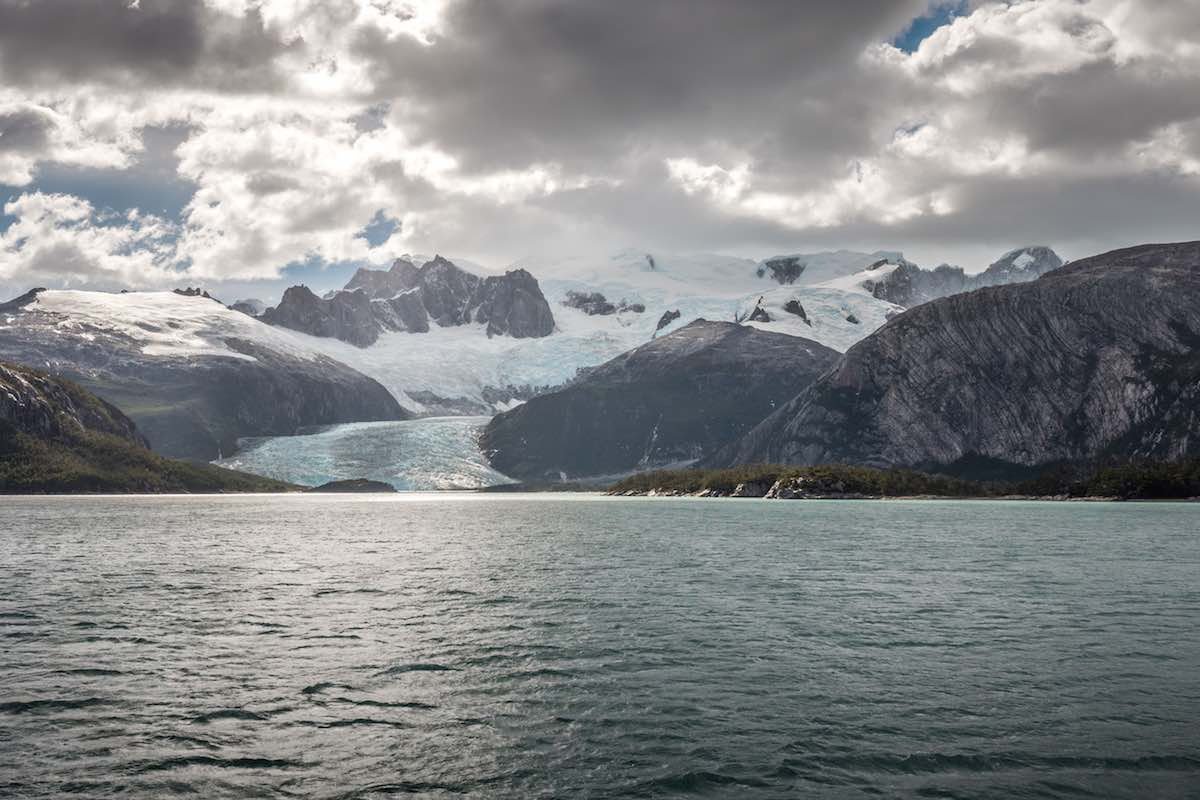 Pia-Fjord-Australis-Tours The Pia Fjord is opens to blue glacier water under a clouded sky.
