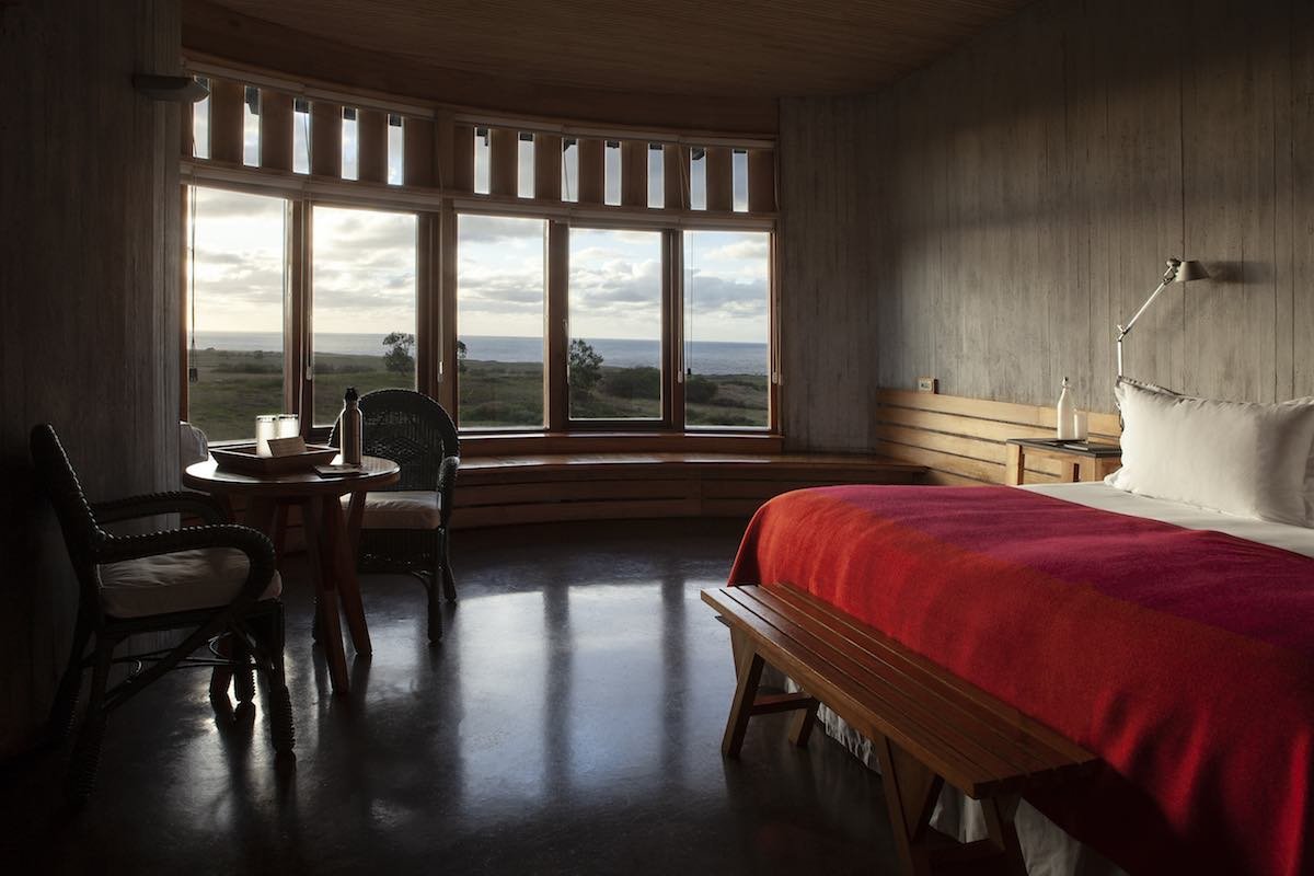Raa-Suite-2-Explora-Rapa-Nui Explora Rapa Nui suites feature red blankets, wood floors, large windows with panoramic views.
