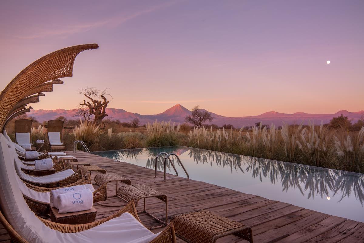 Tierra-Atacama-sunset-infinity-pool Tierra Atacama has a infinity pool with lounge chairs that has mountain and desert views beneath a purple sunset.