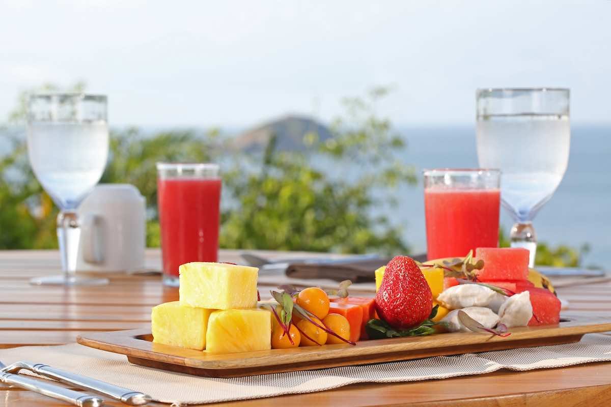 Arenas-del-Mar-fruit-platter A platter of fruit includes pineapple, strawberries, pink smoothies and glasses of water.