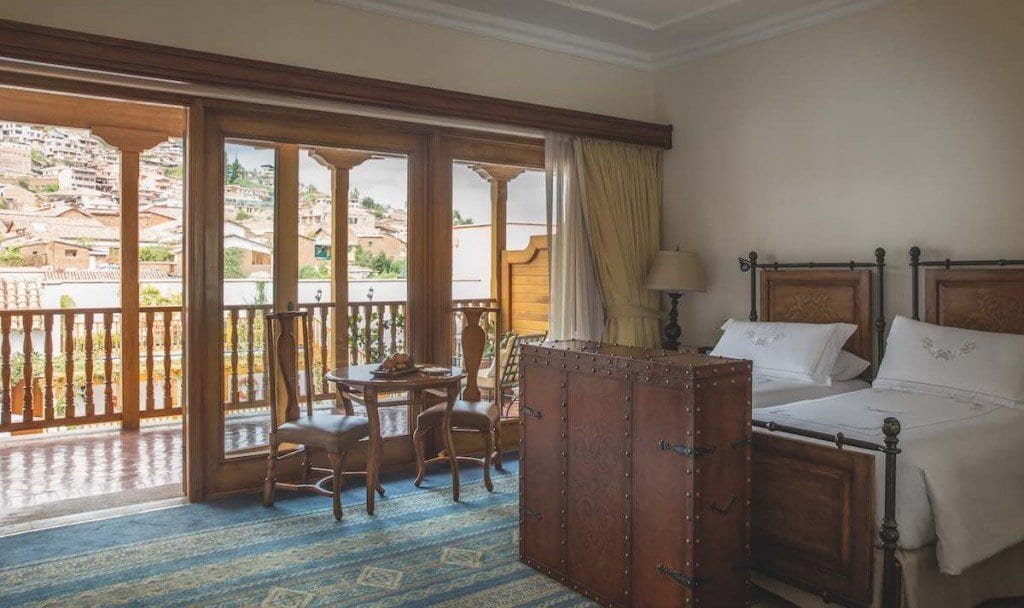 Belmond-Palacio-Nazarenas-Studio-Suite The studio suites at Belmond Palacio Nazarenas feature a colorful blue rug, a terrace balcony, two twin beds and wood furnishings.