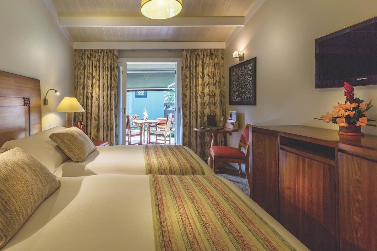 Belmond-Sanctuary-Terrace The room features two twin beds with a window view, tv and curtains.