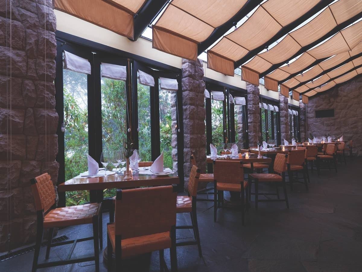 Belmond-Sanctuary-dining-area Belmond Sanctuary lodge includes a dining area with a windowed wall looking out into the mountains.