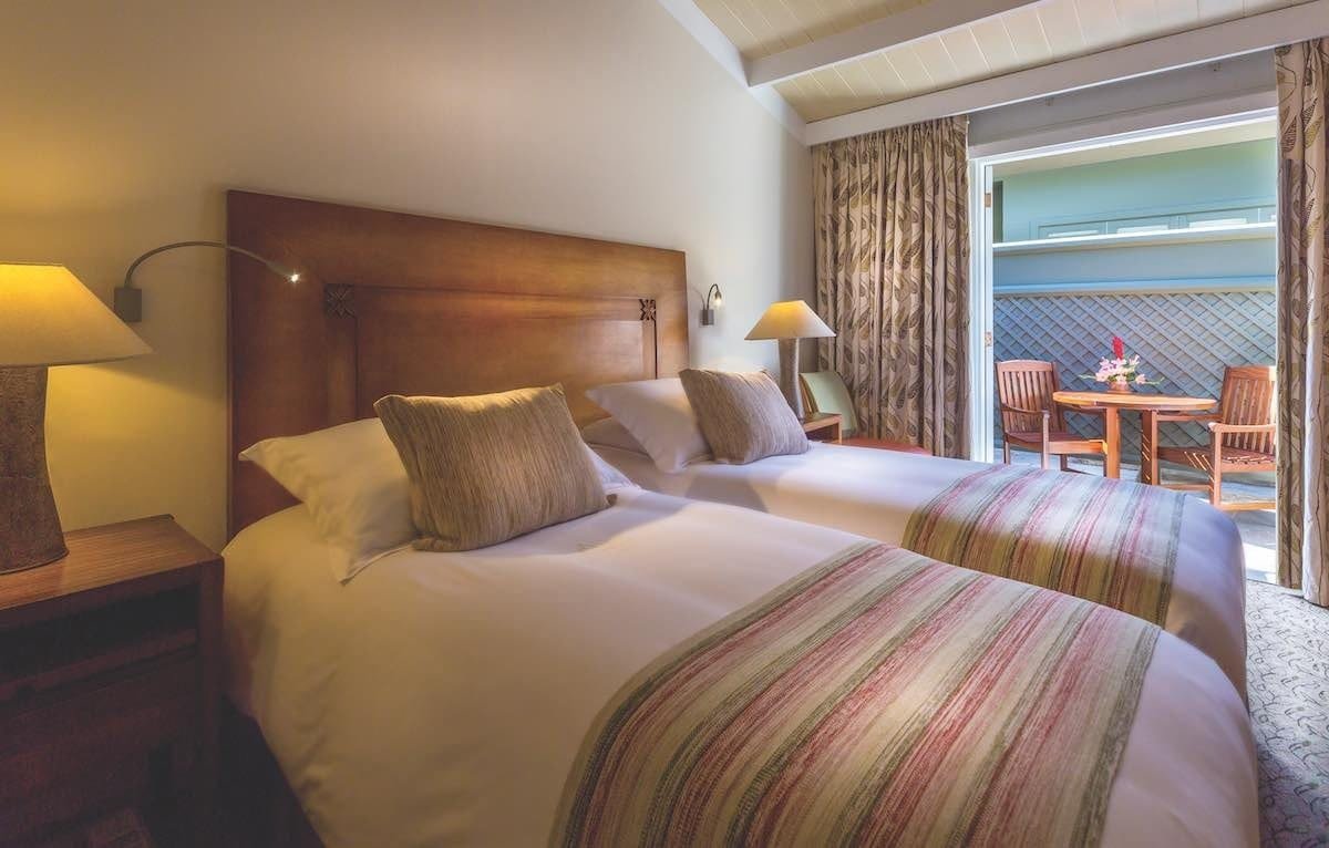 Belmond-Sanctuary-standard-room This room features two twin beds, blankets, and a large window.