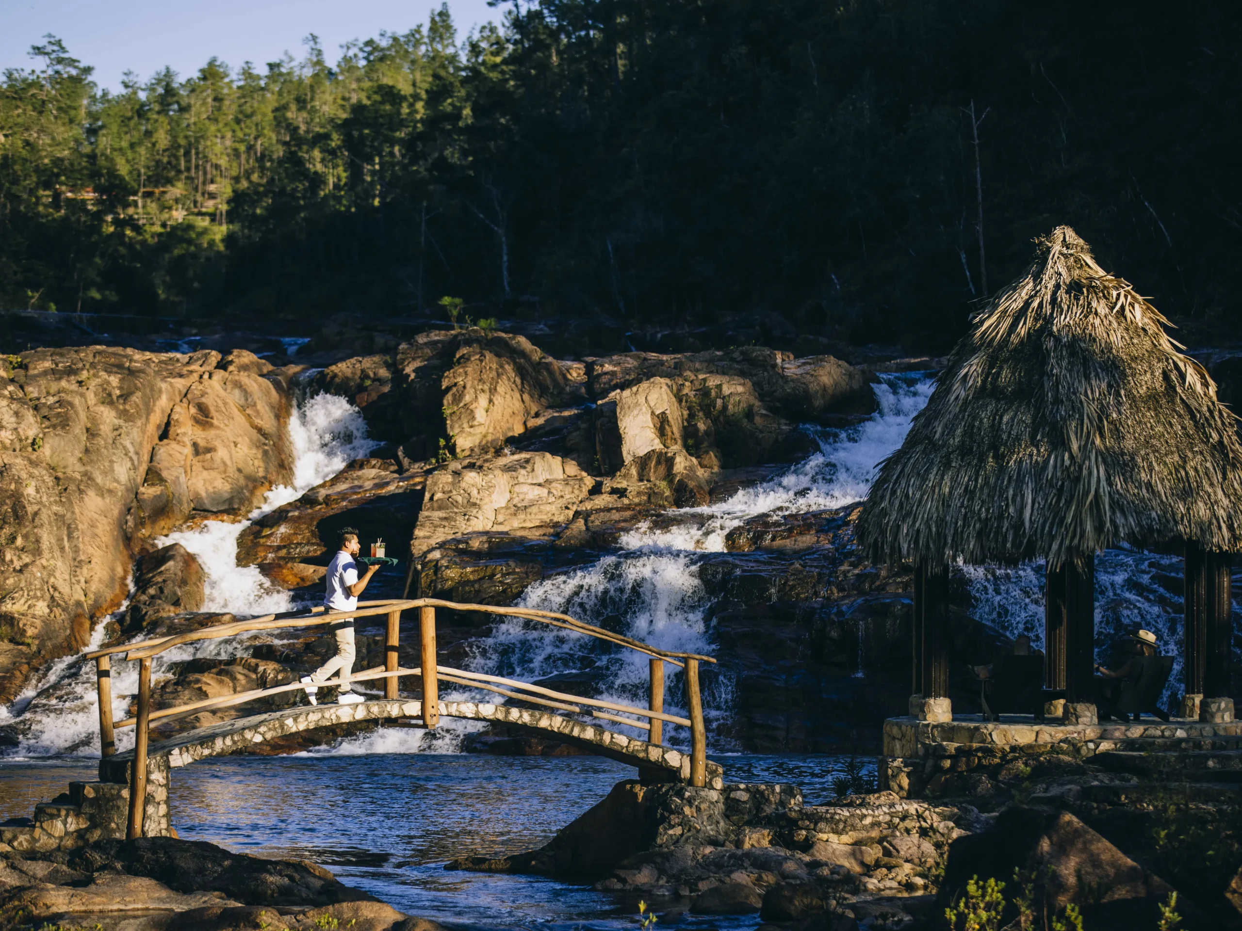 Waiter serves guests that lounge in front of waterfalls.