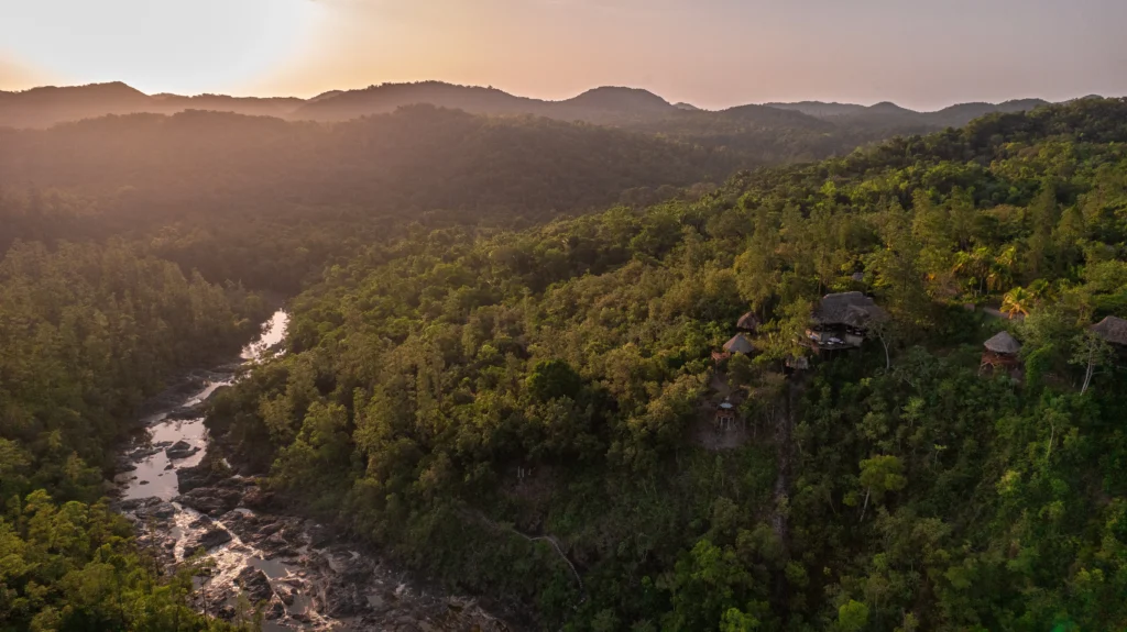 Aerial view of a lodge that rests on the mountains above a river.