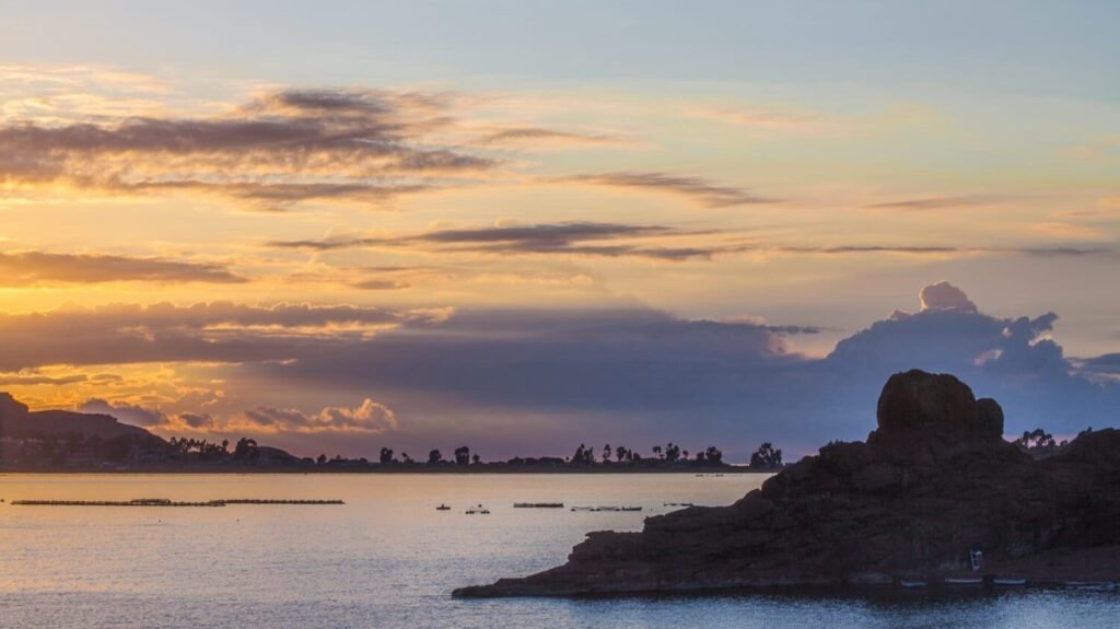 Tranquil Lake Titicaca beneath a cloudy sunset.