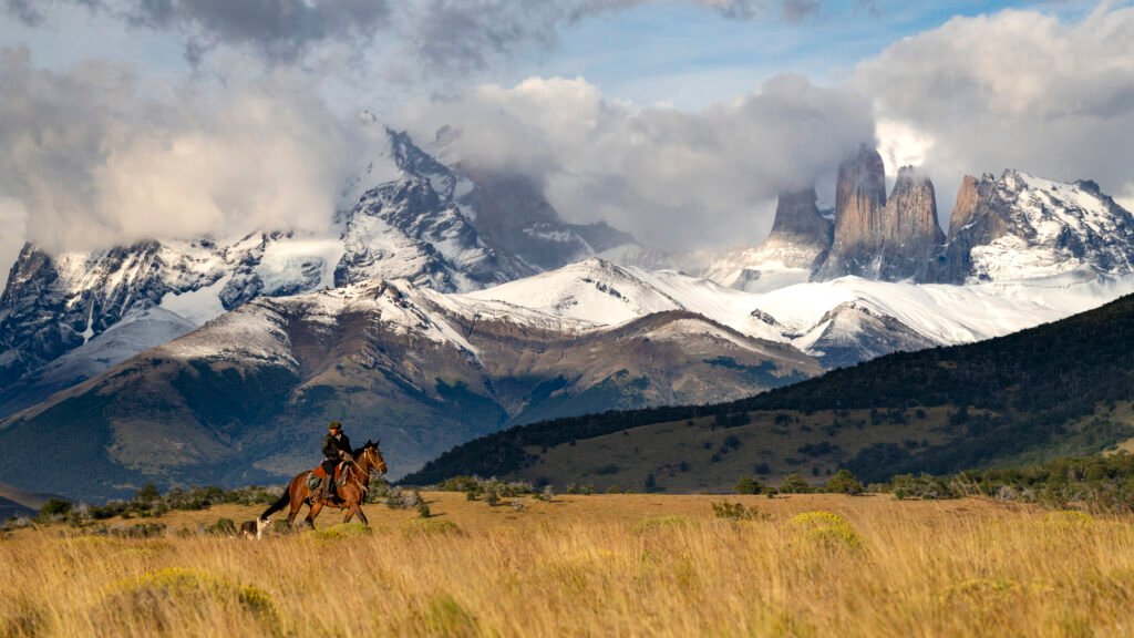 A Gaucho riding on horseback with his dog in Torres del Paine